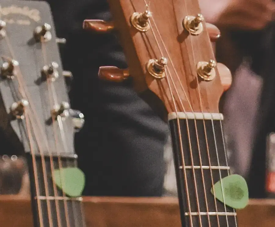 Top section of two guitars with a plectrum placed in the strings